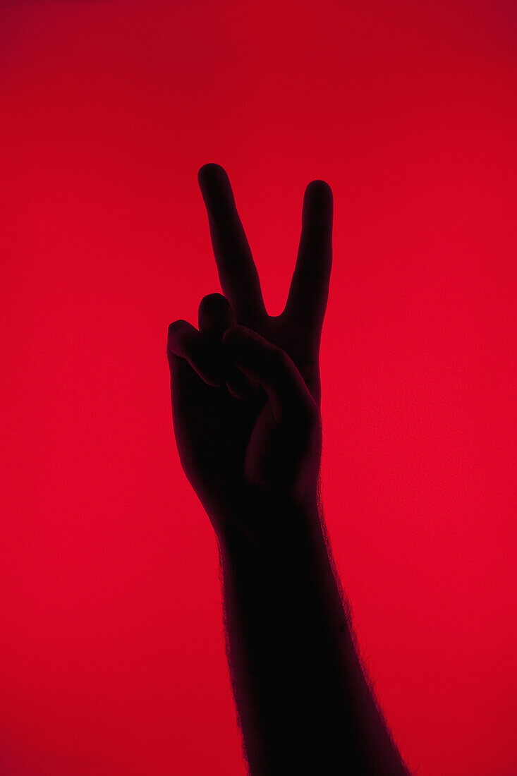 A silhouetted hand making a peace sign