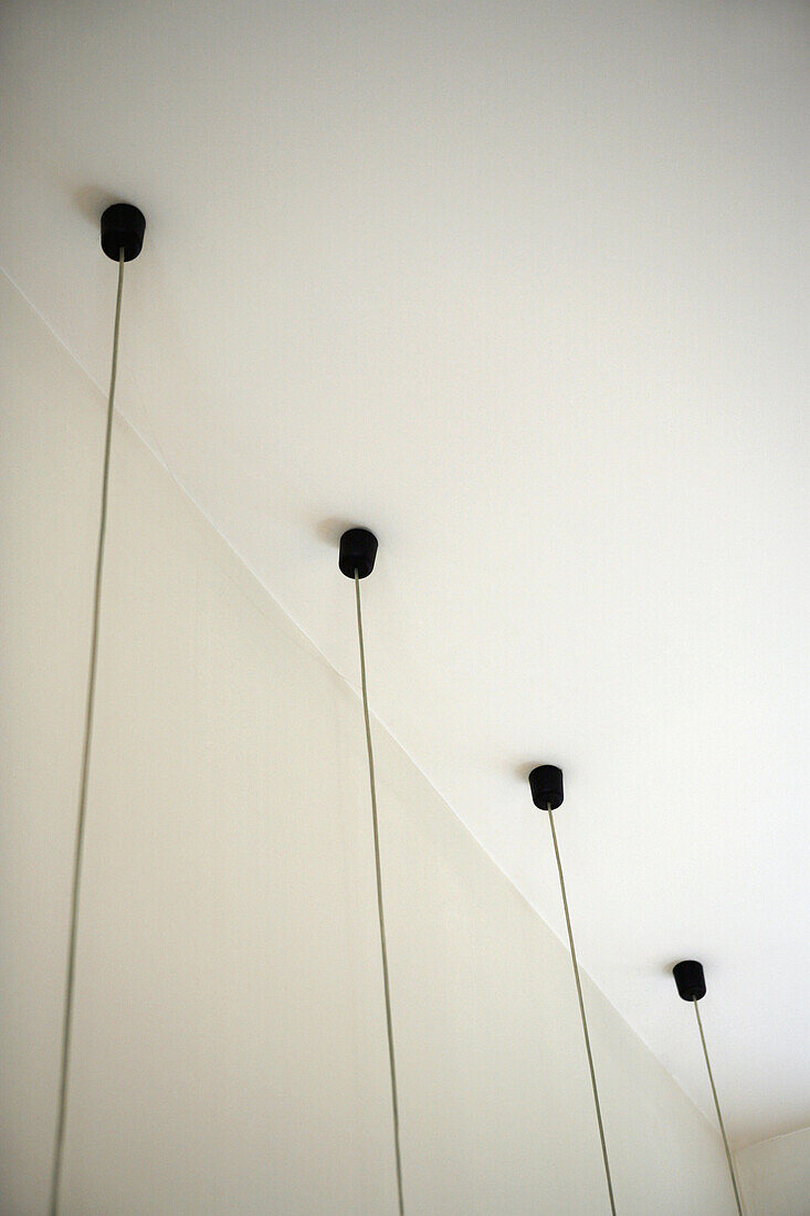 Four light fixtures with cables hanging down from ceiling