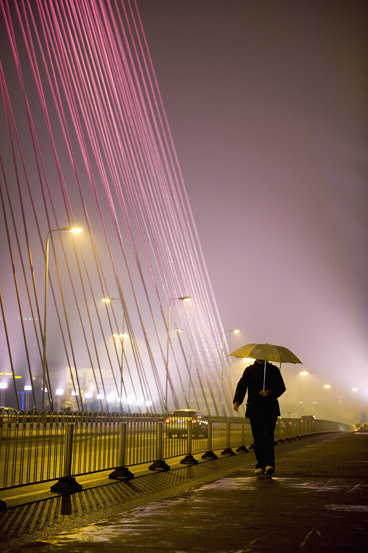 A man walking along a city street, holding an umbrella