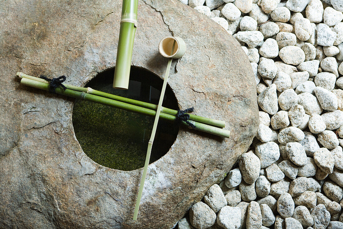 Stone basin with bamboo ladle and gravel, high angle view