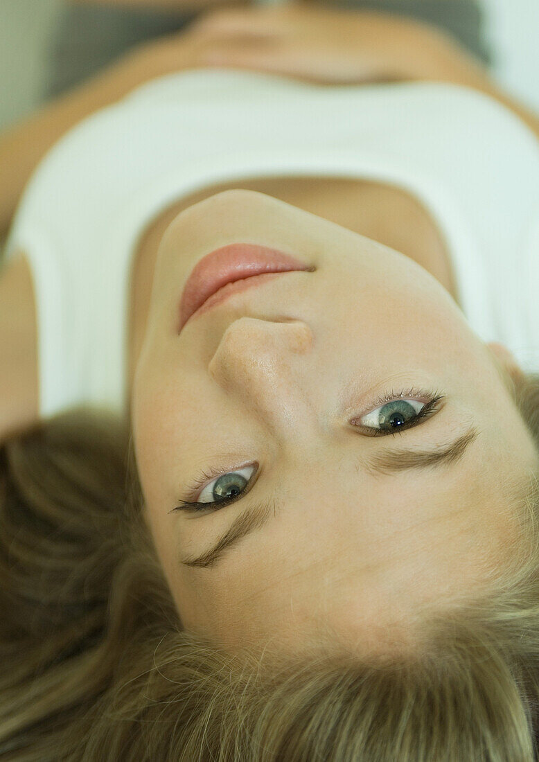 Young woman lying on back, close-up of face, upside down