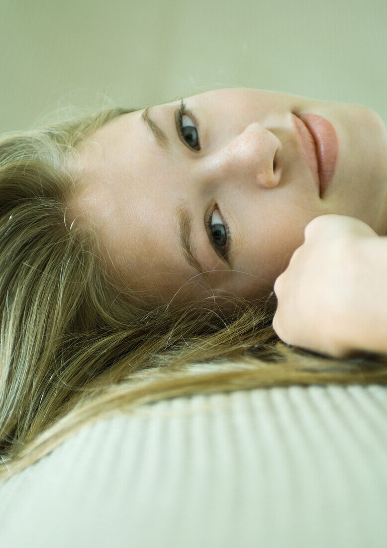 Young woman reclining, smiling at camera, close-up of face