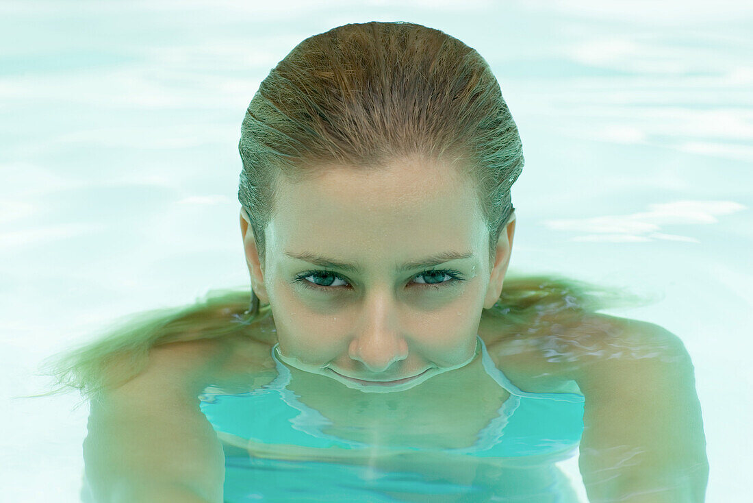 Young woman in pool, head emerging from water