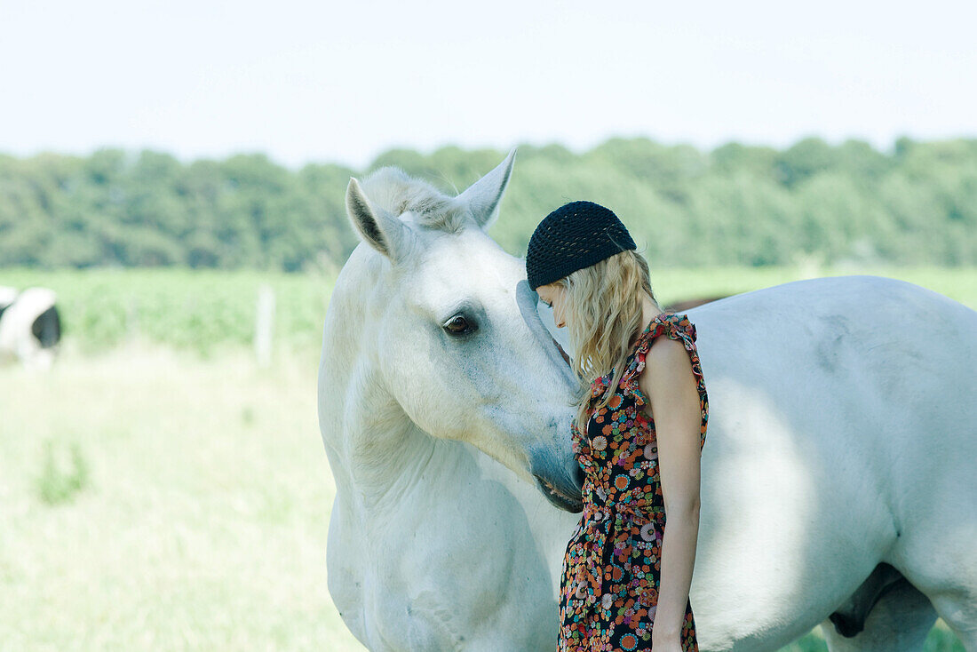 Young woman leaning her head against horse