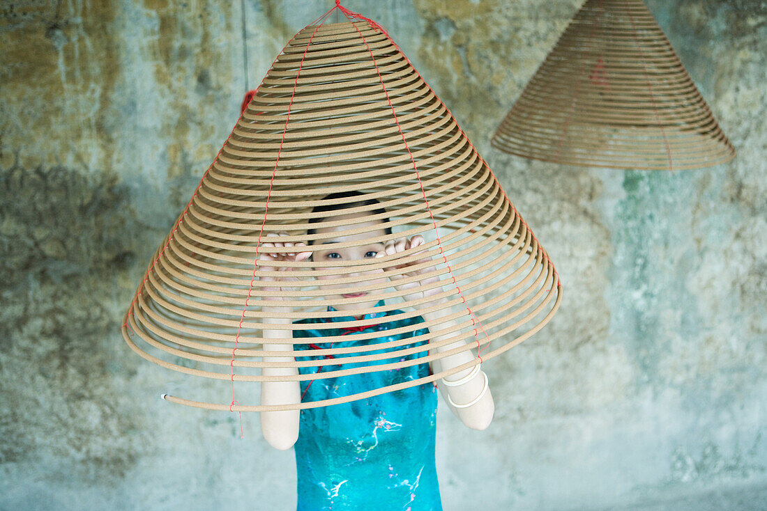 Young woman wearing traditional Chinese clothing, looking through spiral of incense