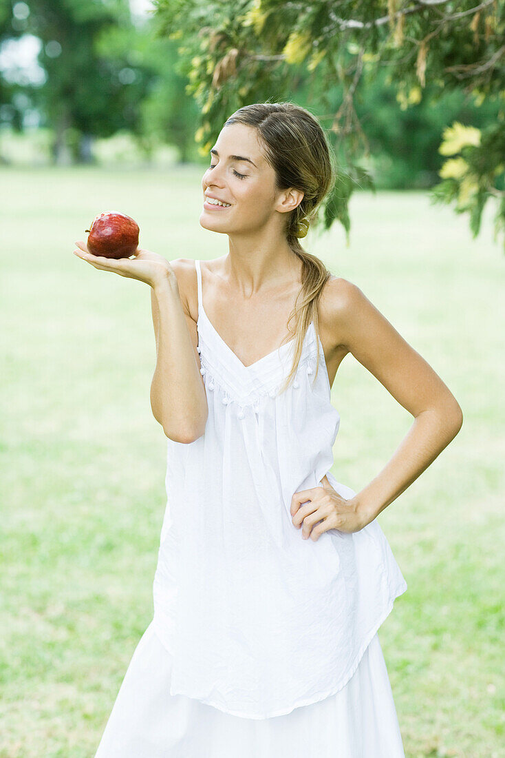 Woman balancing apple on palm of hand, smiling