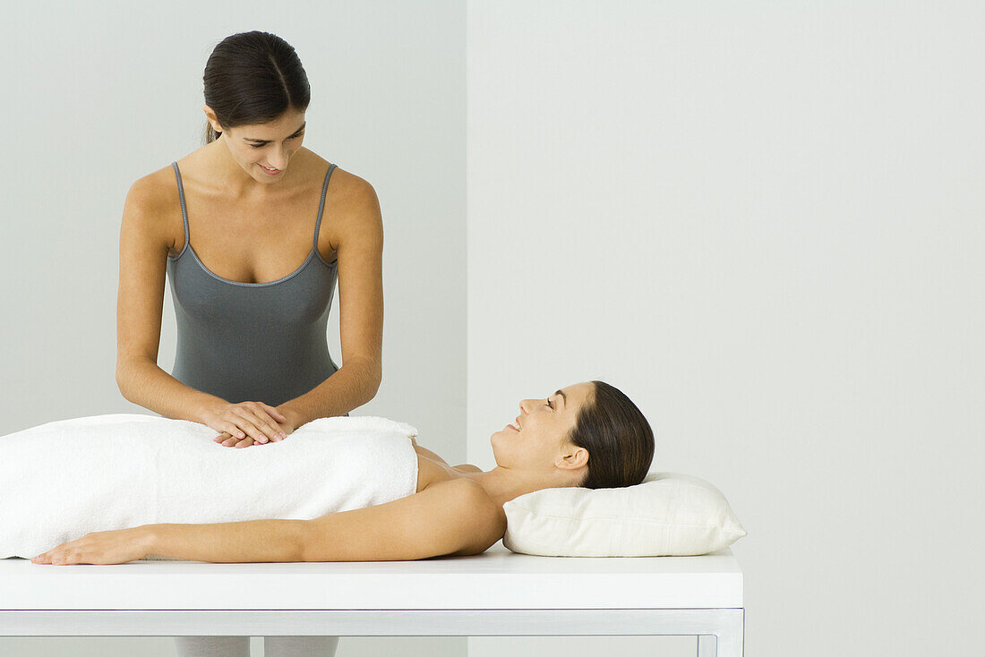 Woman receiving massage, chatting with massage therapist
