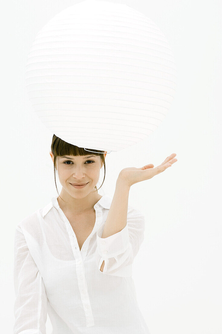 Woman looking underneath paper lantern, smiling at camera