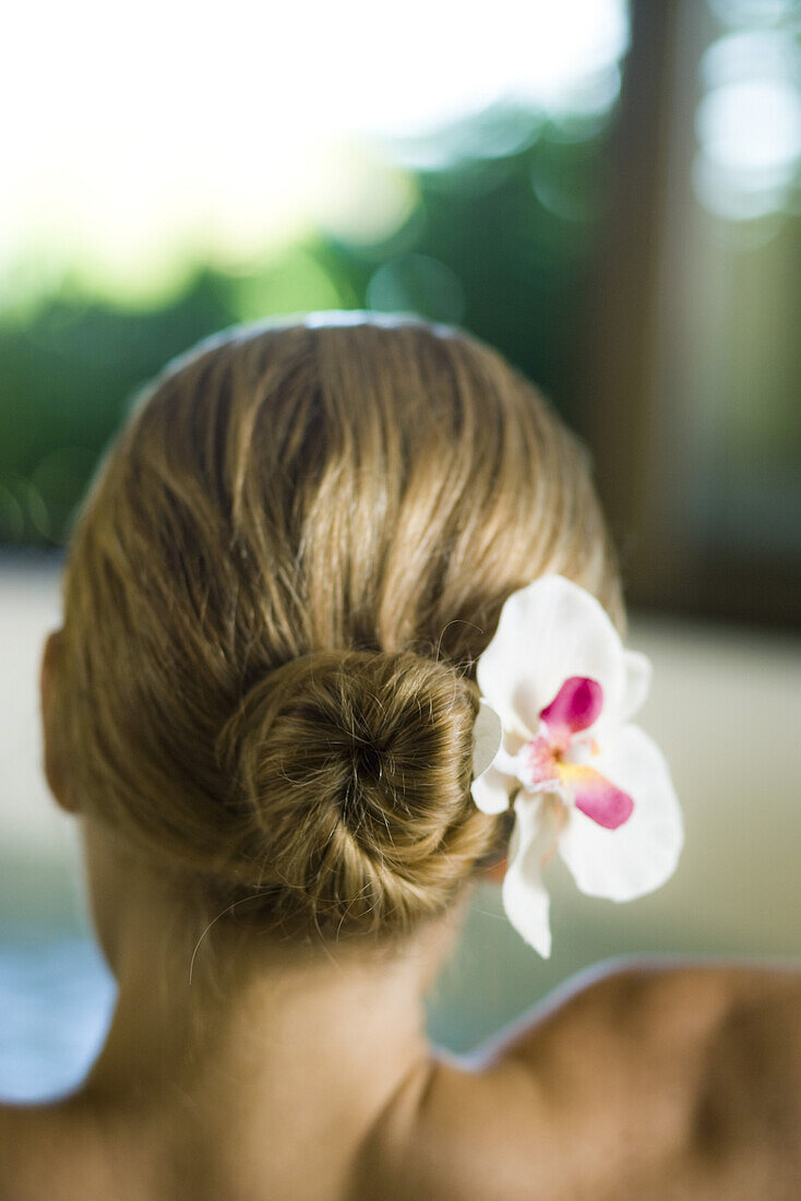 Woman with orchid in hair, rear view
