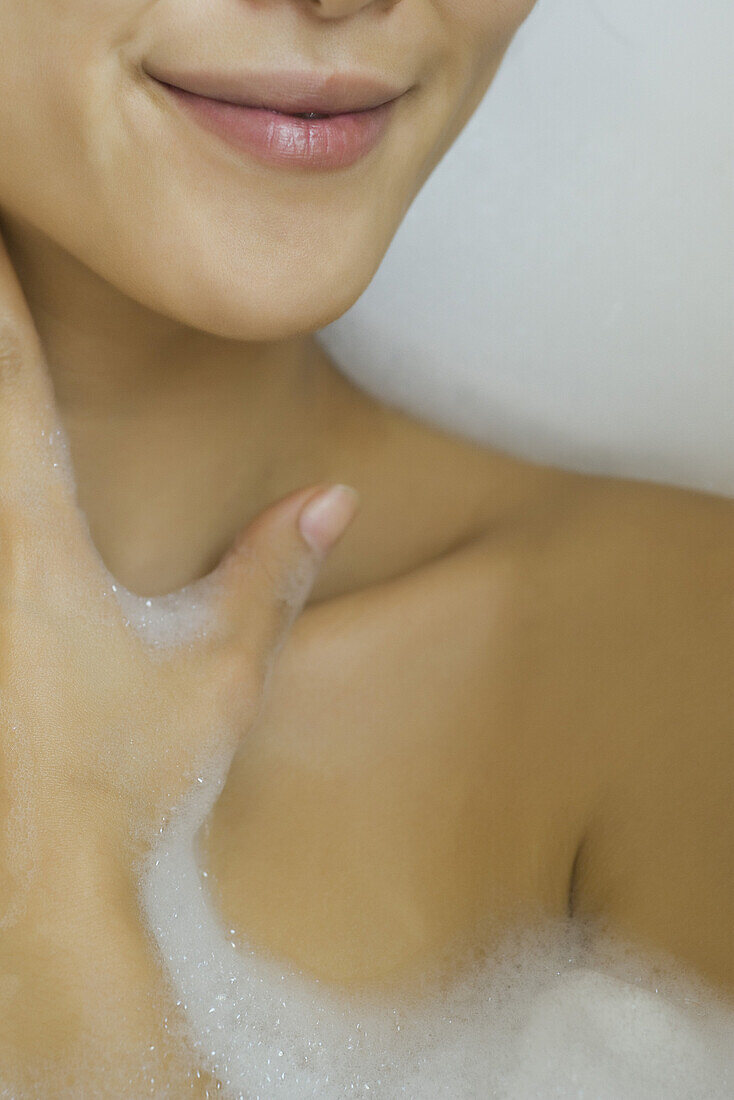 Woman soaking in bubble bath, cropped