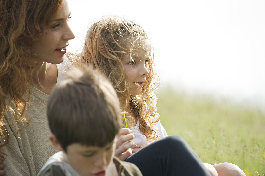 Mother and two children relaxing together outdoors