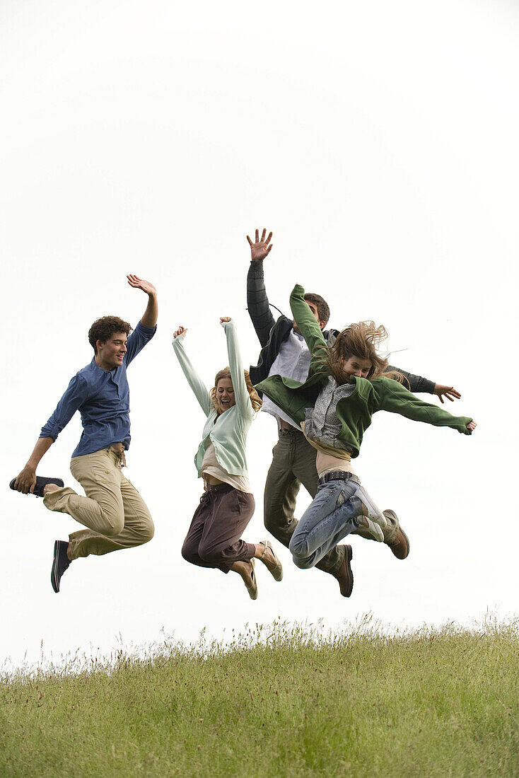 Young adults jumping on meadow