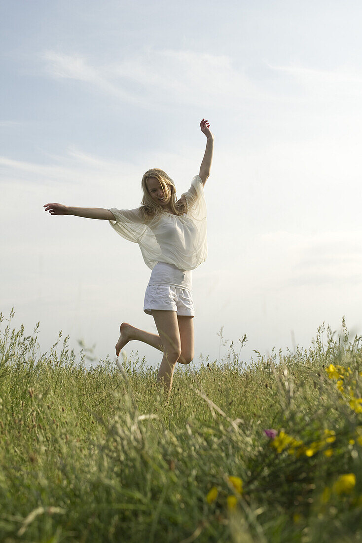 Young woman jumping in meadow