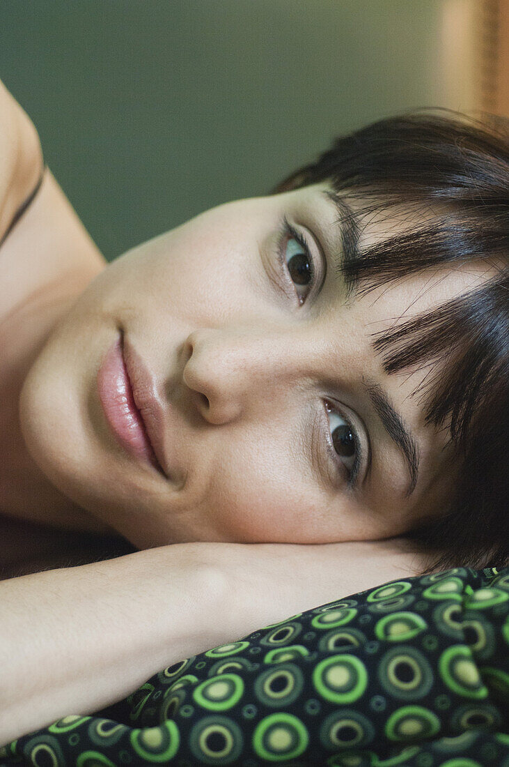 Young woman resting head on arm, smiling, portrait