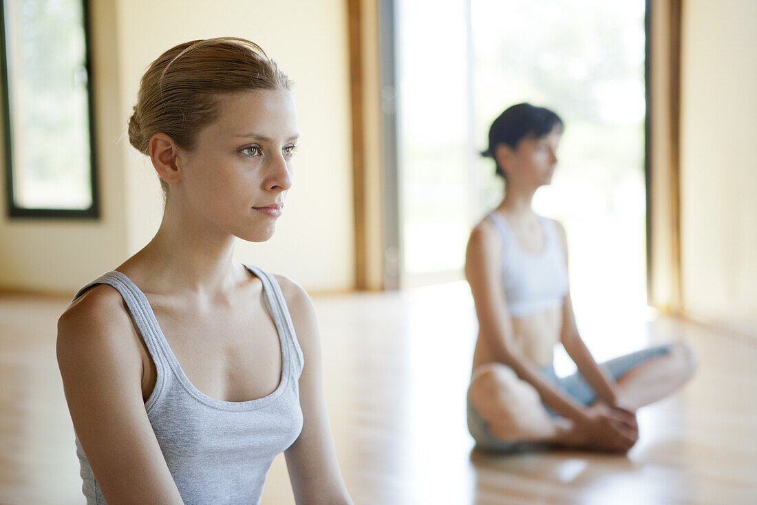 Junge Frau sitzt im Lotussitz in einer Yogastunde