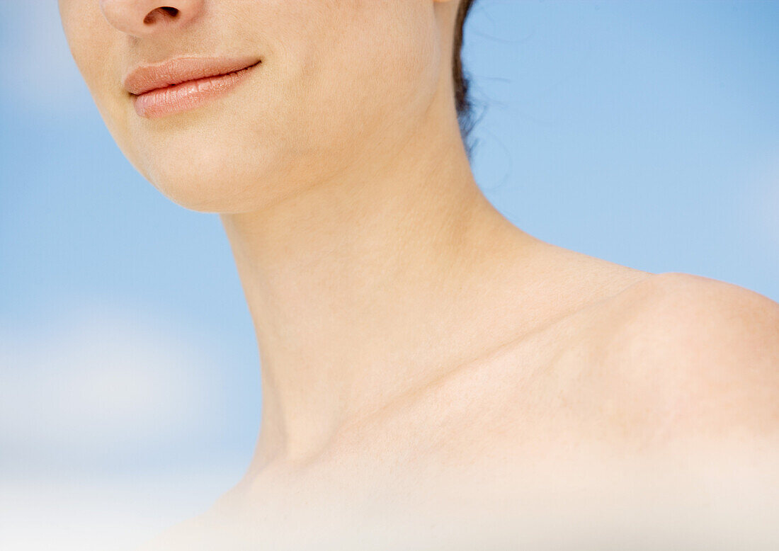Woman's lower face and shoulder, sky in background