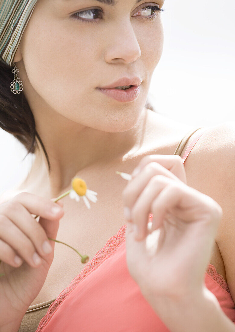 Young woman plucking petal off flower