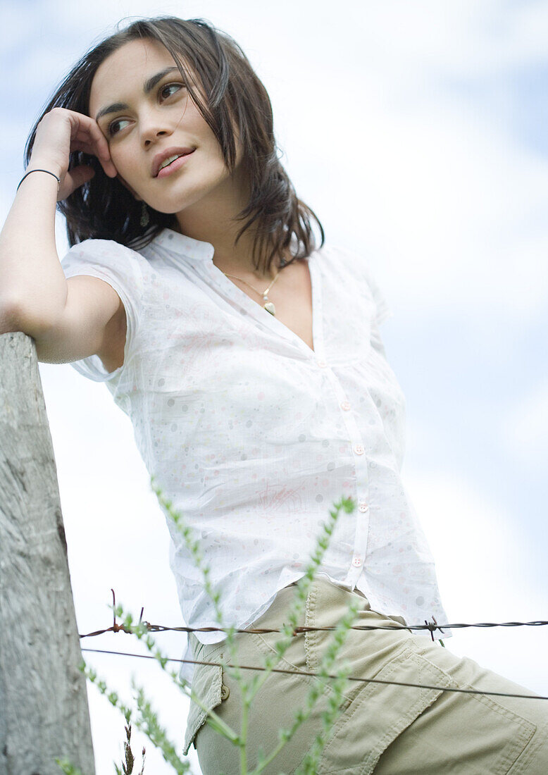 Woman leaning on fence post