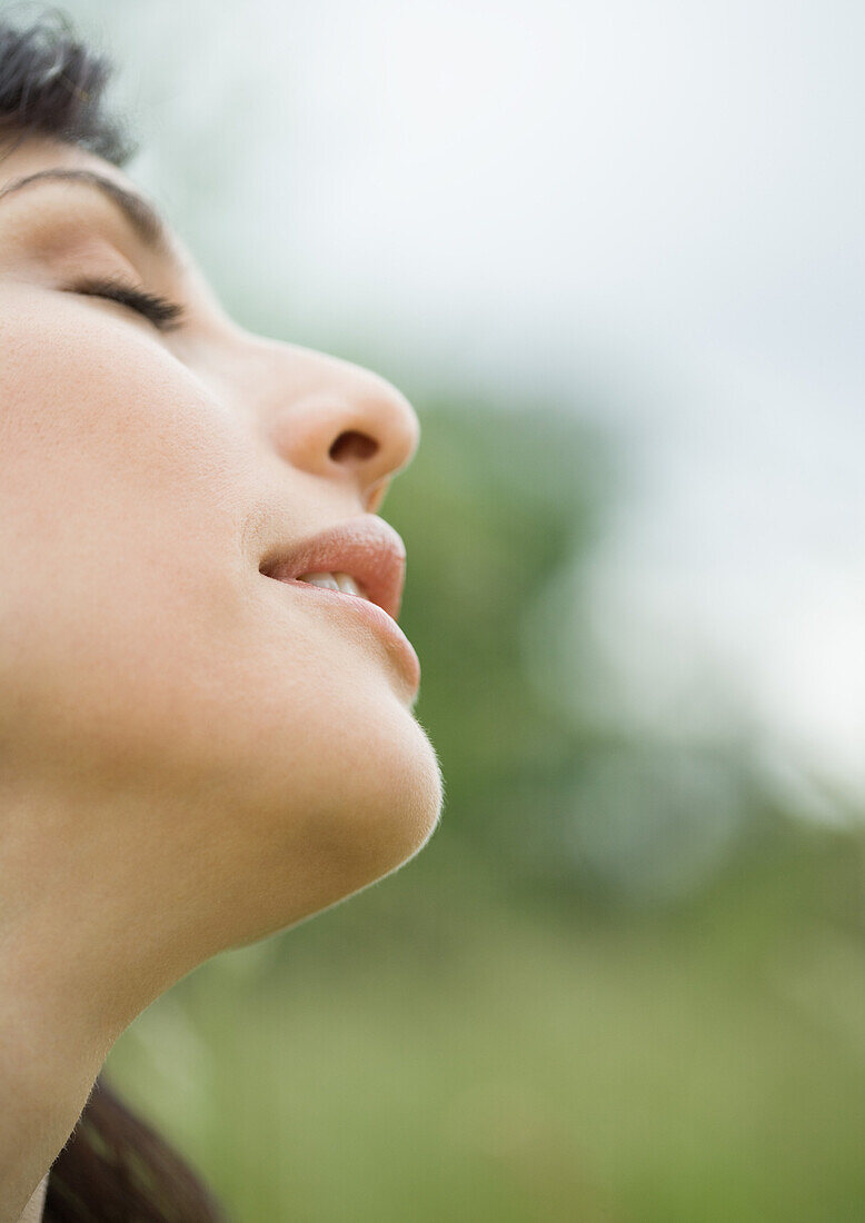 Woman closing eyes and tilting head back, close-up, side view