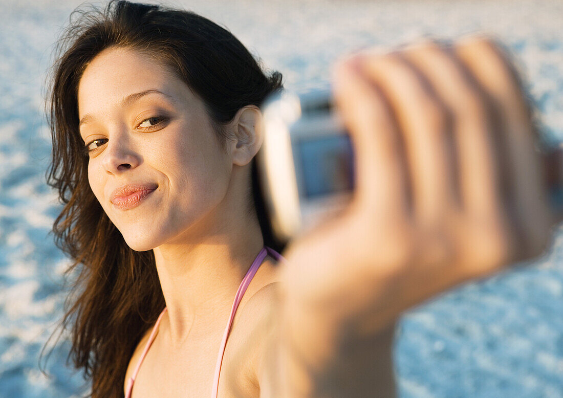 Young woman taking photo of self on beach