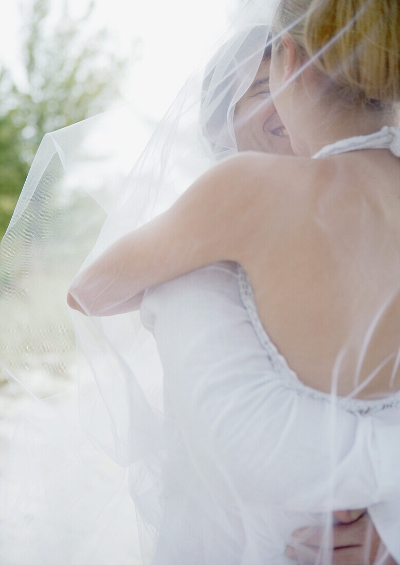 Bride and groom embracing under veil