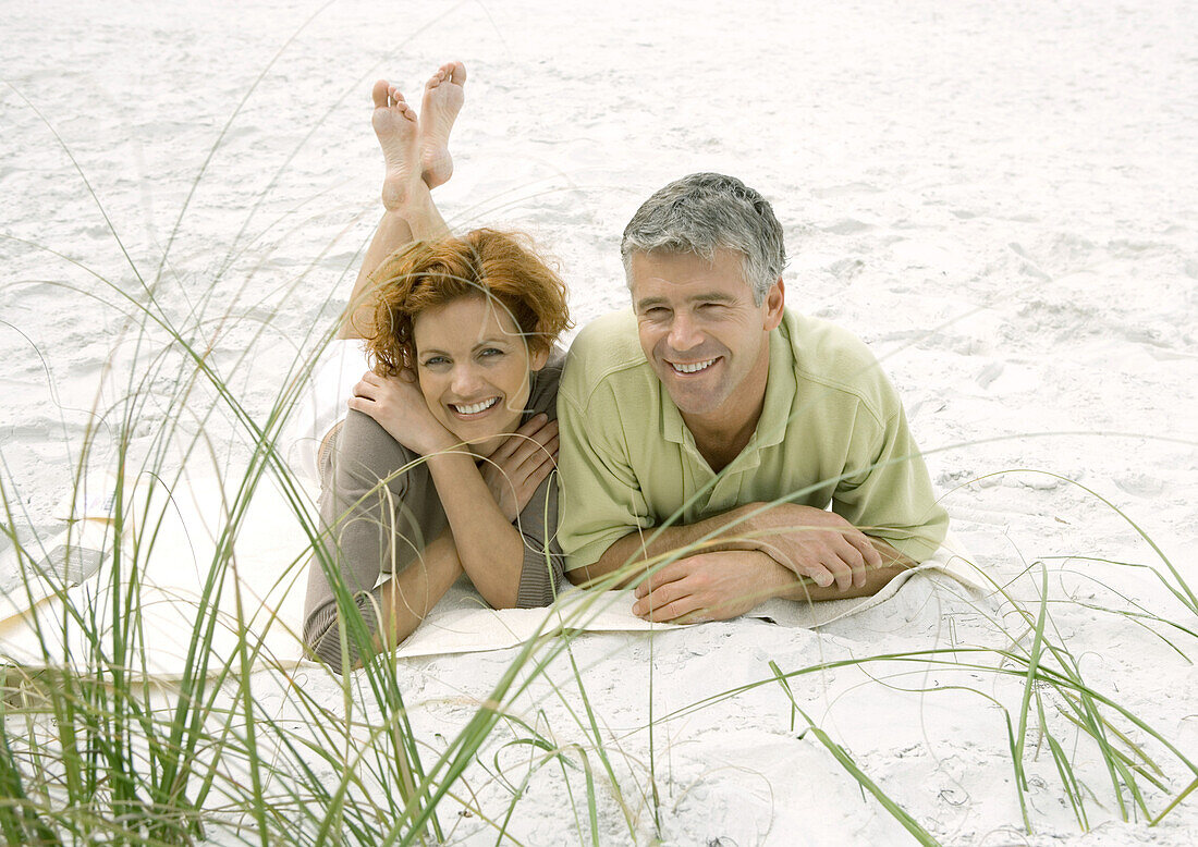 Mature couple lying on beach, front view