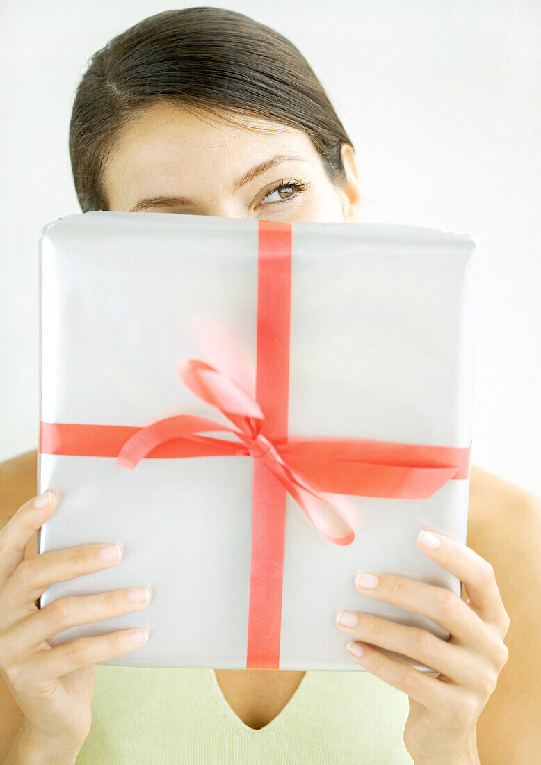 Woman holding present in front of face