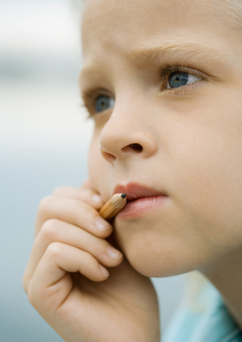 Girl holding pencil next to mouth