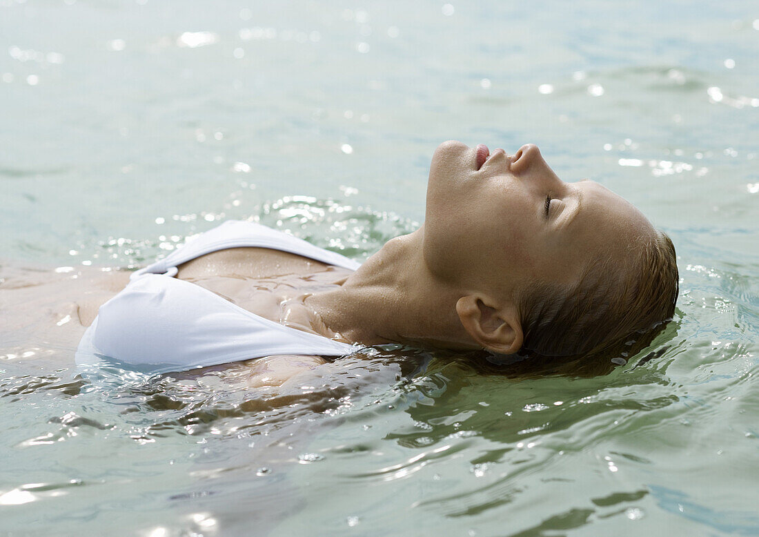 Woman in water with head back and eyes closed