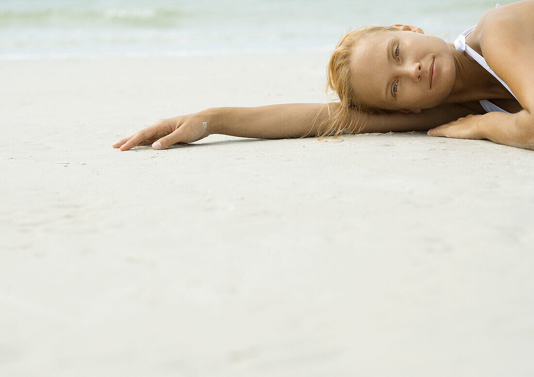Woman lying on beach, looking at camera