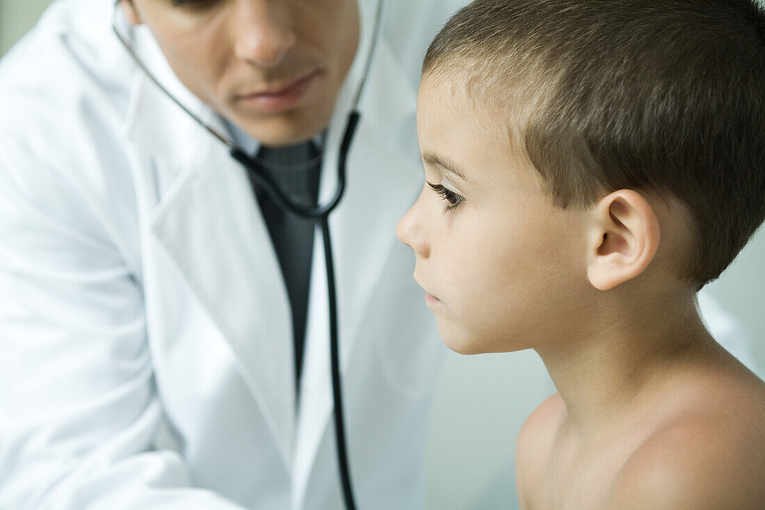 Doctor leaning toward boy with stethoscope