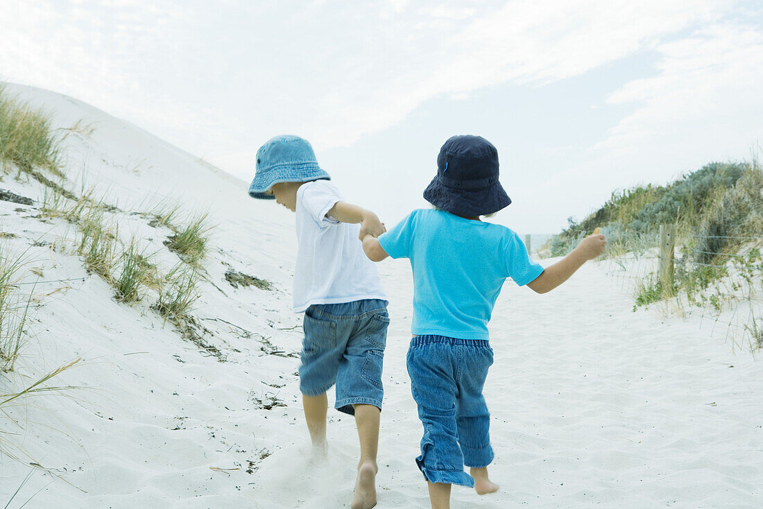 Children running through dunes, holding hands