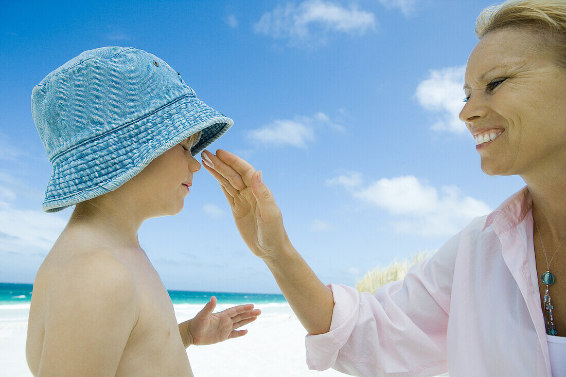 Mother putting sunscreen on child at beach