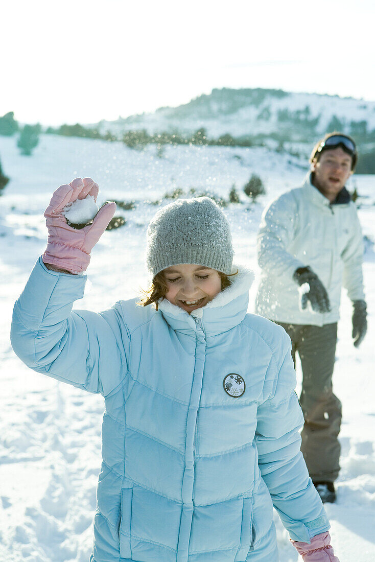 Brother and sister throwing snowballs, girl's eyes closed