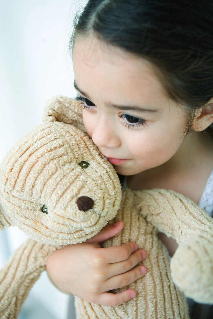 Little girl holding teddy bear, looking away, portrait