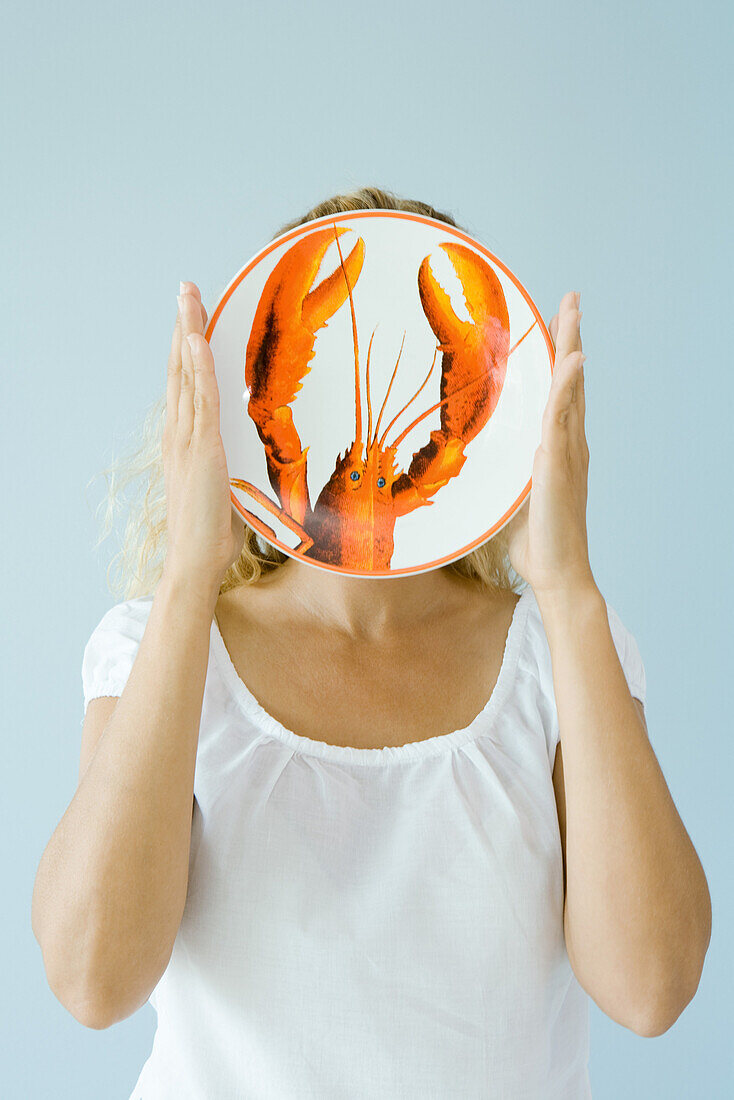 Woman holding up lobster plate in front of face