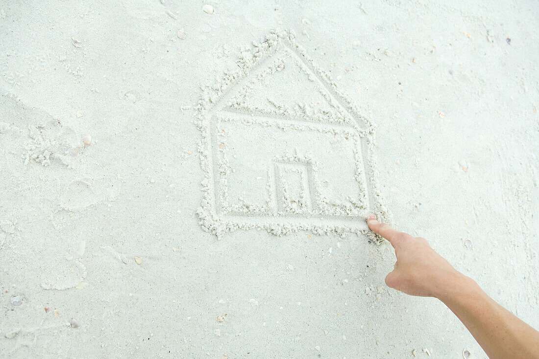 Hand drawing house in sand, cropped view