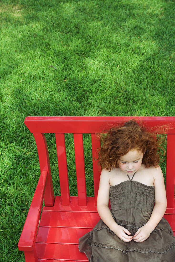 Little girl sitting on bench, eyes closed, high angle view