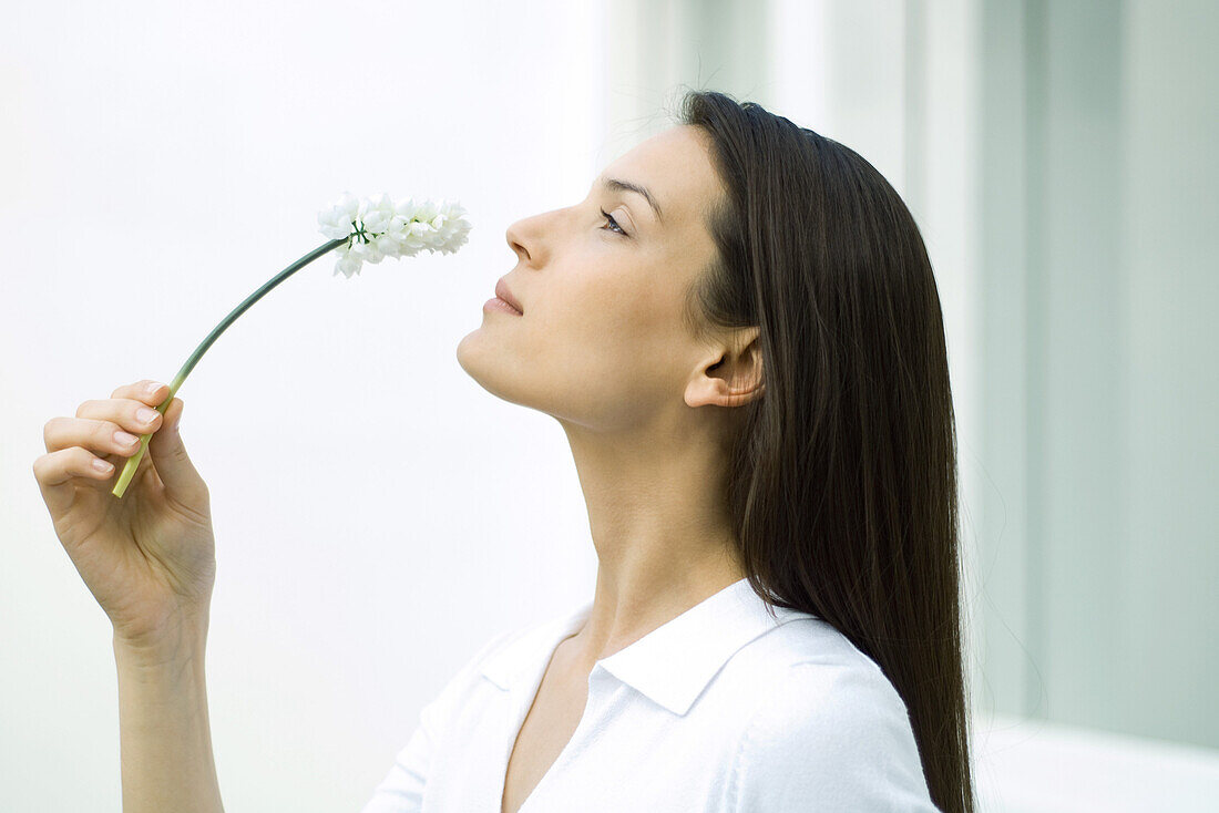 Woman smelling flower, head back, side view