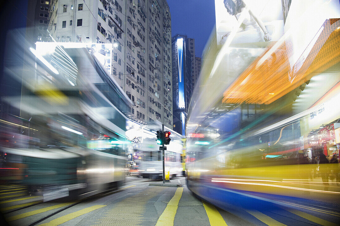 Buses moving through a city at night, blurred motion