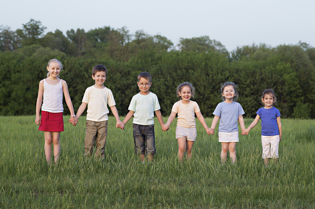 Portrait of children holding hands in a field