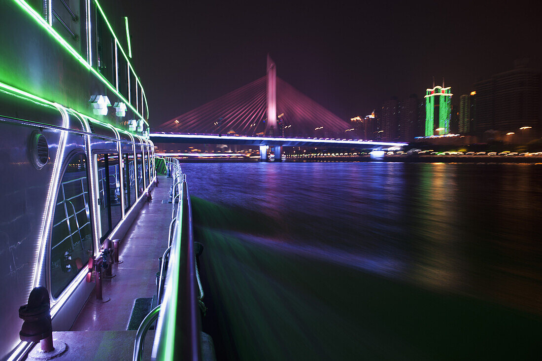 Yacht on Pearl River in Hong Kong and illuminated Haiyin Bridge in background