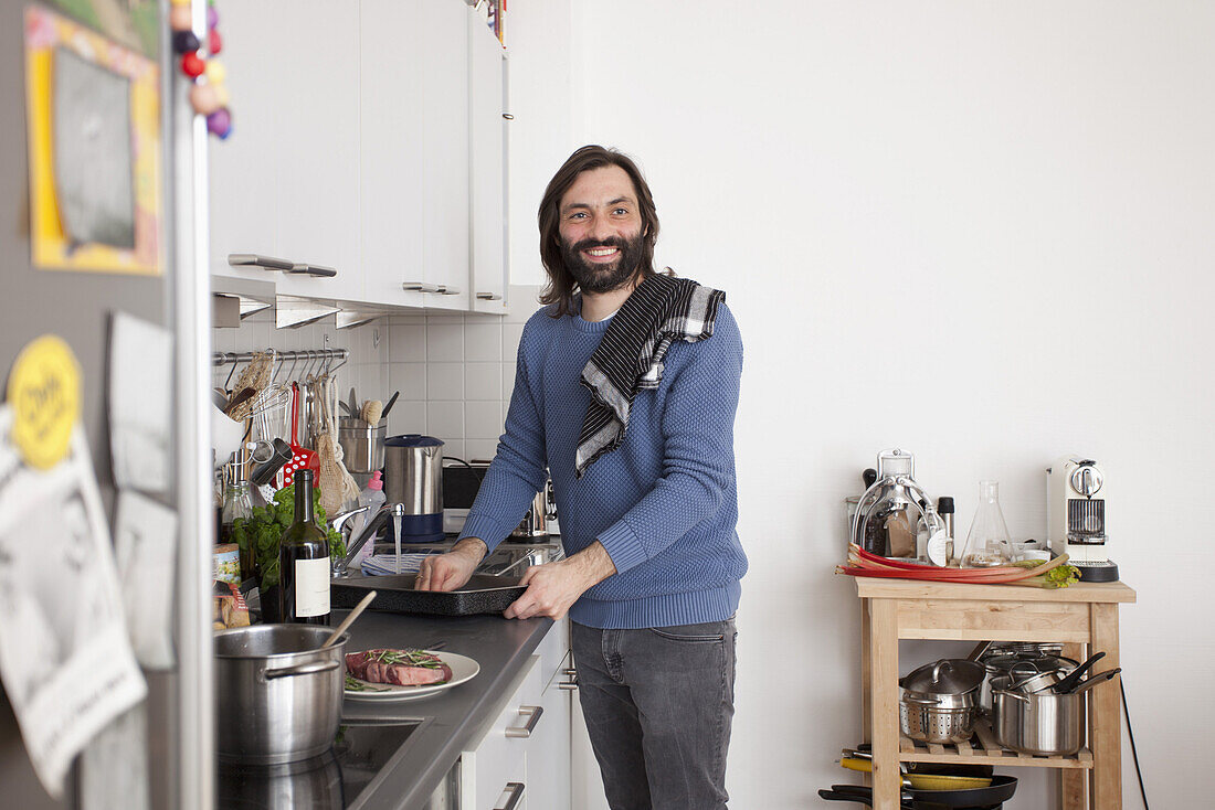 Smiling man looking away while preparing food in domestic kitchen