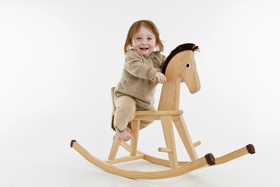 A baby girl on a rocking horse