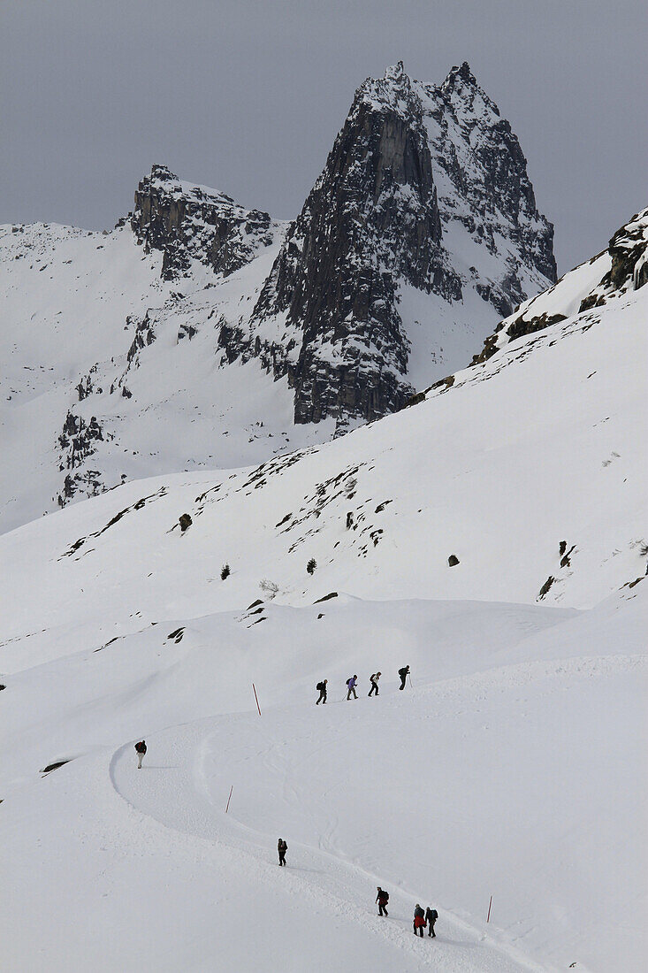 People hiking up a snowy mountain footpath