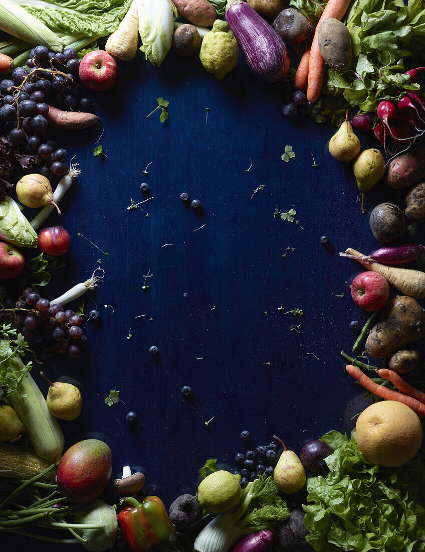 Directly above shot of fresh vegetables and fruits forming circle on blue table