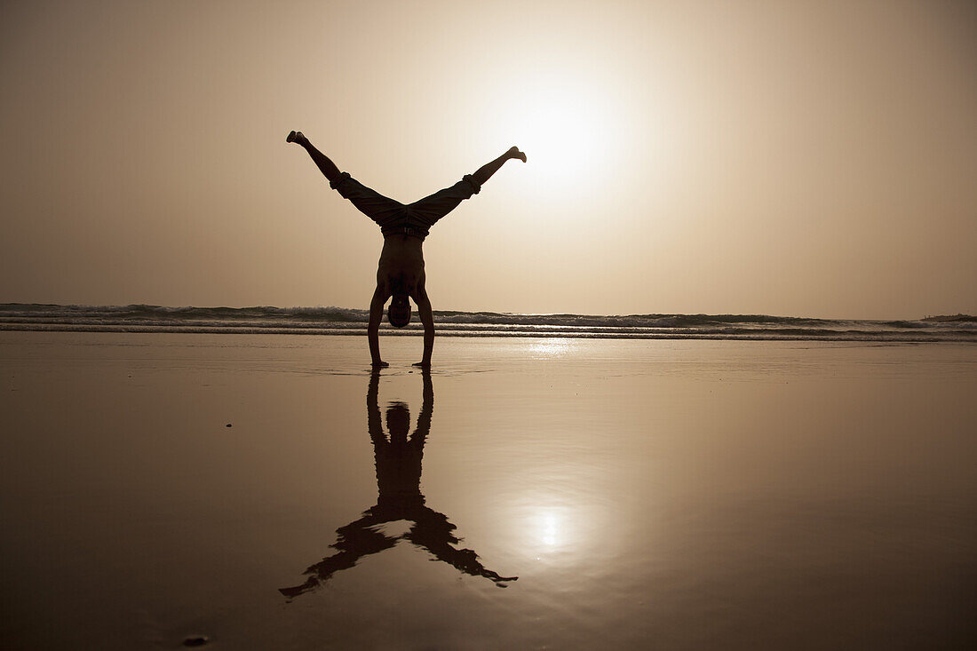 Full length of silhouette man performing handstand at beach