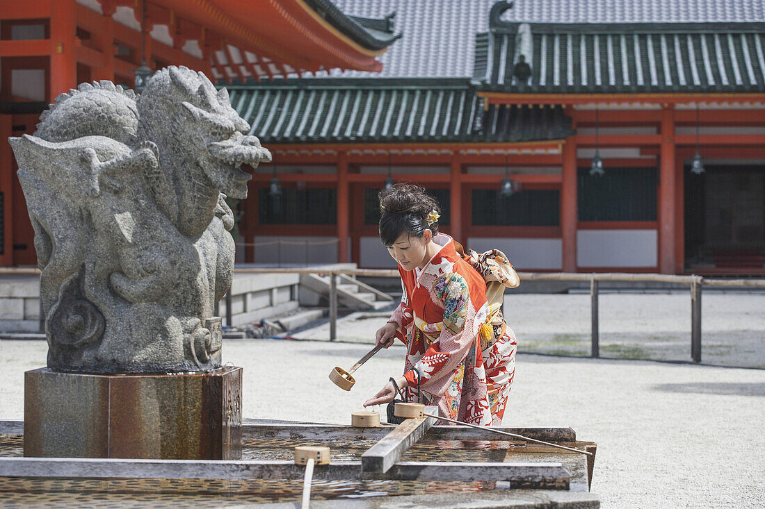 Mid adult woman washing hand against temple