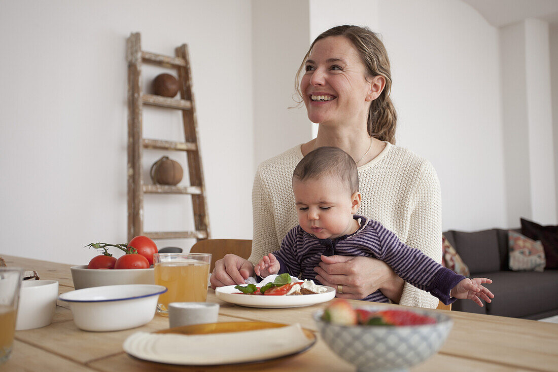 Happy woman looking away while sitting with baby girl at home