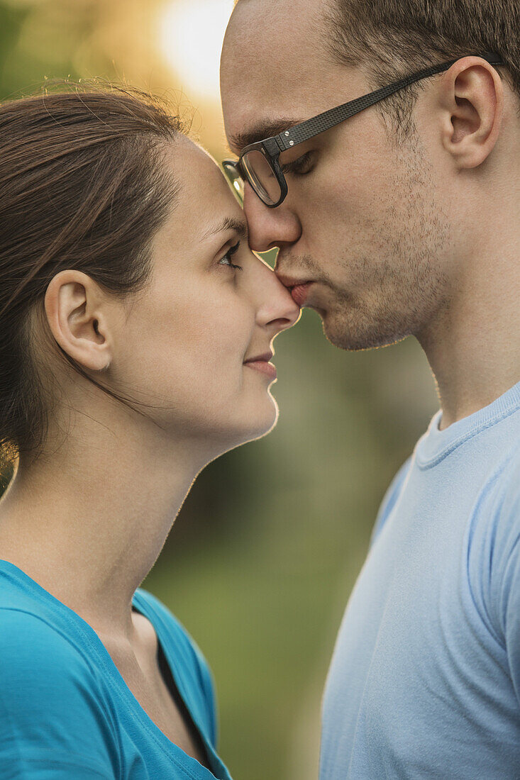 Side view of young man kissing woman on nose in park
